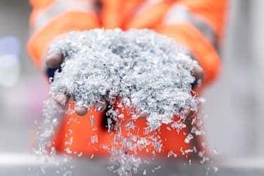 Fabrikarbeiter präsentiert zwei Hände voller Rezyklate. Recycling stärkt die Kreislaufwirtschaft und trägt zur CO2-Reduktion bei. 
