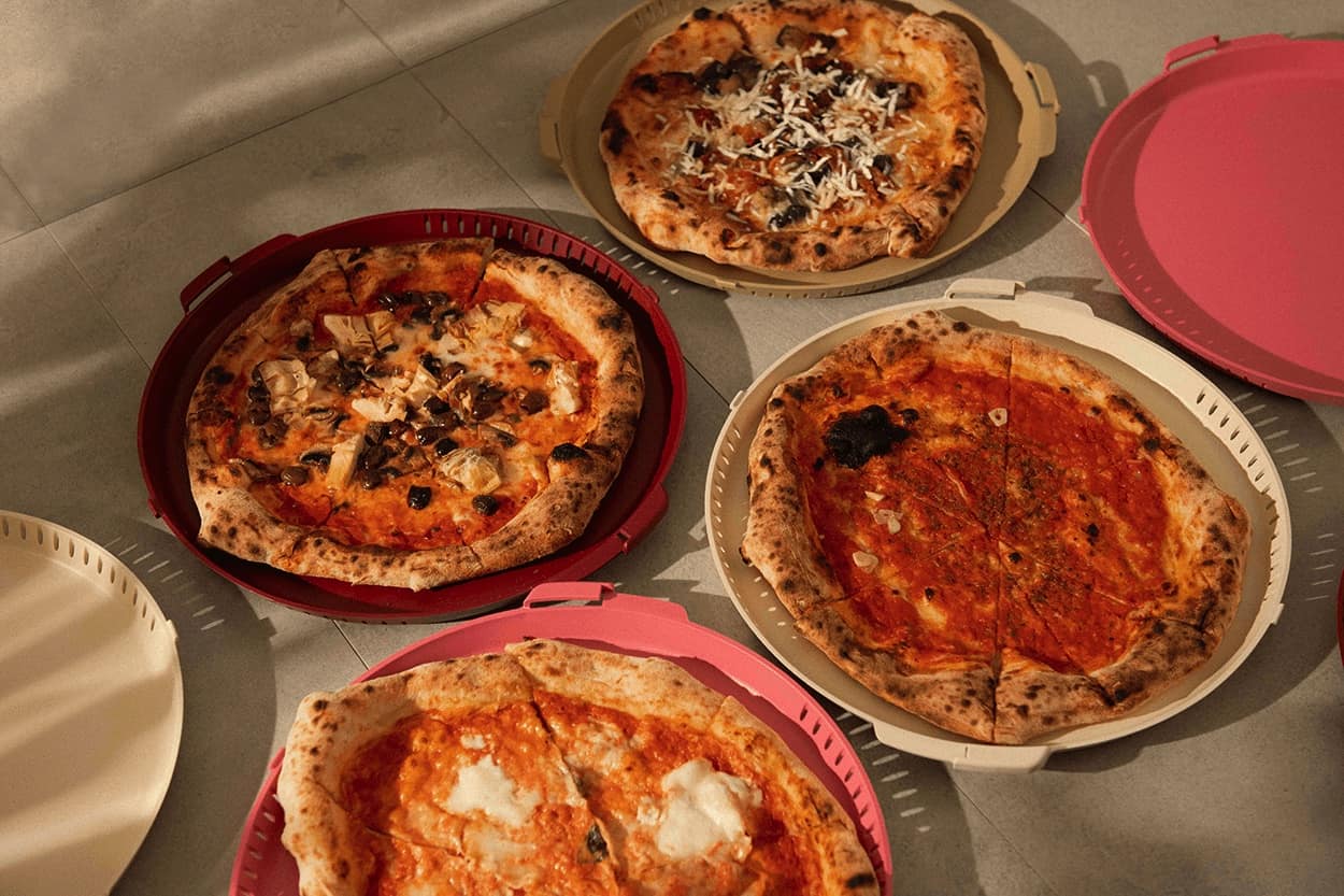Die Mehrwegverpackungen von PIZZycle stellen die nachhaltige Alternative zum Pizzakarton dar. Abgebildet sind mehrere Verpackungen von PIZZycle in verschiedenen Farben.