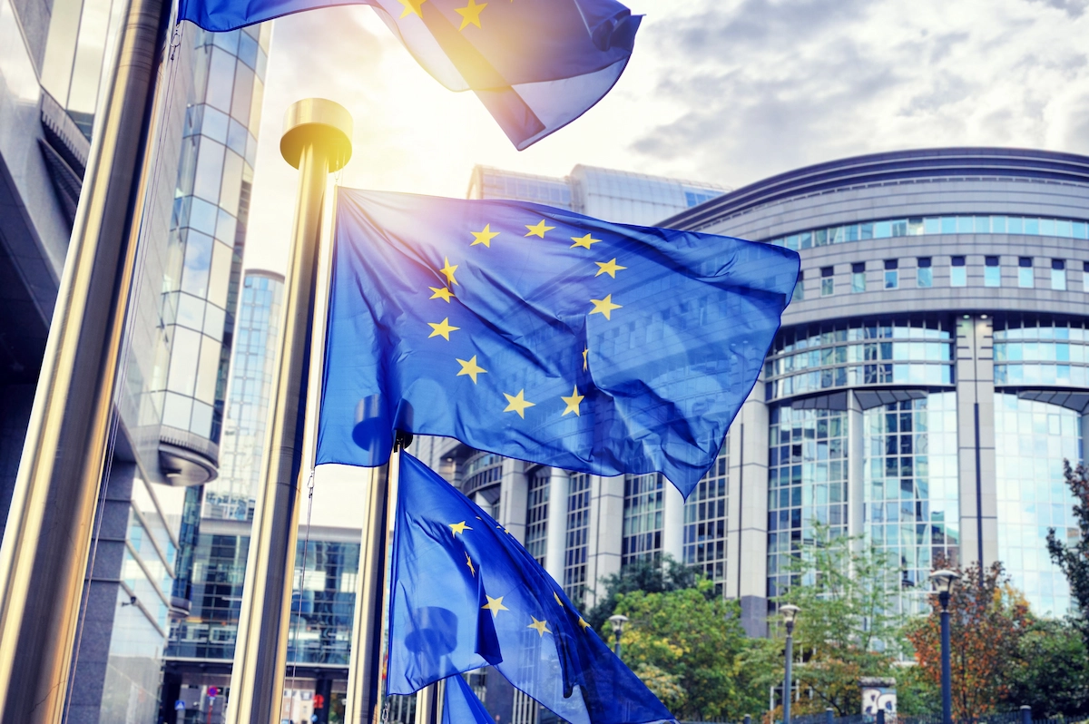 EU Parlament Gebäude mit Flaggen im Vordergrund.